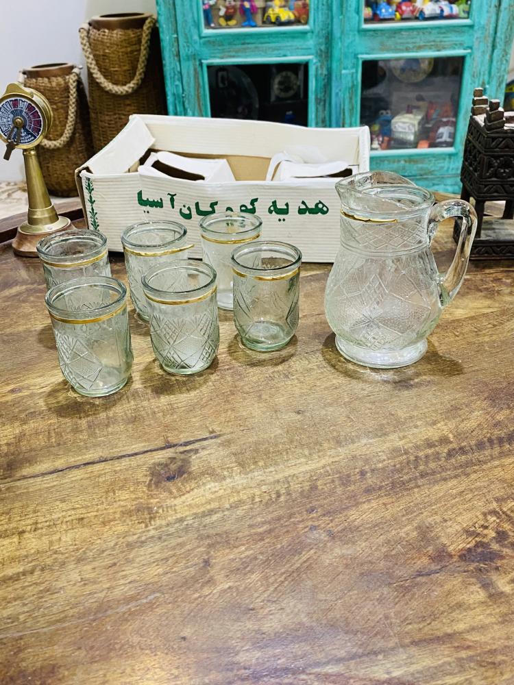 طقم ديكوري من الزجاج المتين جداً بمقاس صغير عبارة عن جيك بإرتفاع ١٥ سم تقريباً وعدد ٦ كاسات بحجم بيالة الشاهي تقريباً؛ قديم ومخزن بالكرتون لم يستخدم