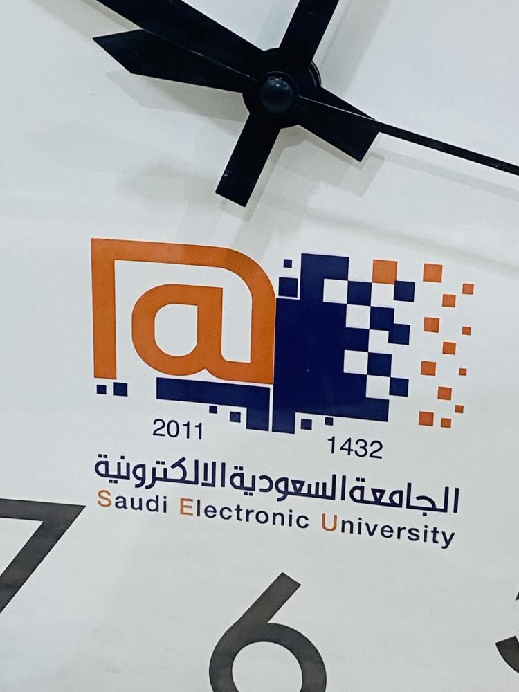 من البنود المميزة؛ ساعة حائط دعائية بمناسبة افتتاح الجامعة السعودية الإلكترونية عام ١٤٣٢هـ؛ علماً أنه تم تغيير مسمى الجامعة إلى جامعة الأمير مساعد بن عبدالرحمن؛ الساعة مخزنة بالكرتون الخاص بها لم تستخدم