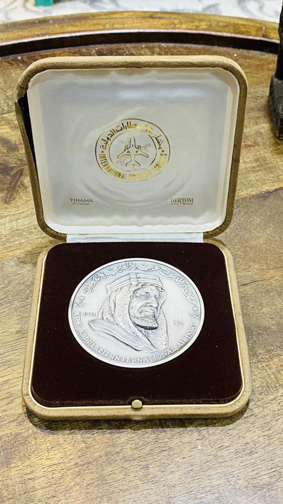 من البنود الشحيحة؛ علبة فاخرة جداً بداخلها ميدالية معدنية ثقيلة الوزن بحجم كبير (واضح حجمها مقارنة بالعملة التي بجانبها فئة الريال) وهي رمزية لمطار الملك عبد العزيز الدولي مؤرخة بعام ١٤٠١هـ - ١٩٨١م تم سكّها في إيطاليا (مقتنى عالي التميز)