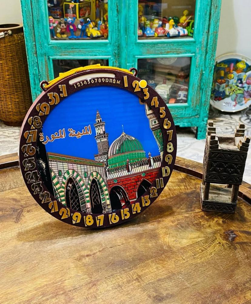 من النوادر؛ تعليقة جدارية بتقويم يدوي بالأشهر والأيام يتم تغيير الأيام بالدبوس الأصفر الواضح في الصور وبداخل التقويم صورة للحرم المكي والحرم المدني بلونين للإطار البني والأزرق؛ قديمة ومخزنة بالكرتون تخزين ممتاز؛ صناعة اليابان