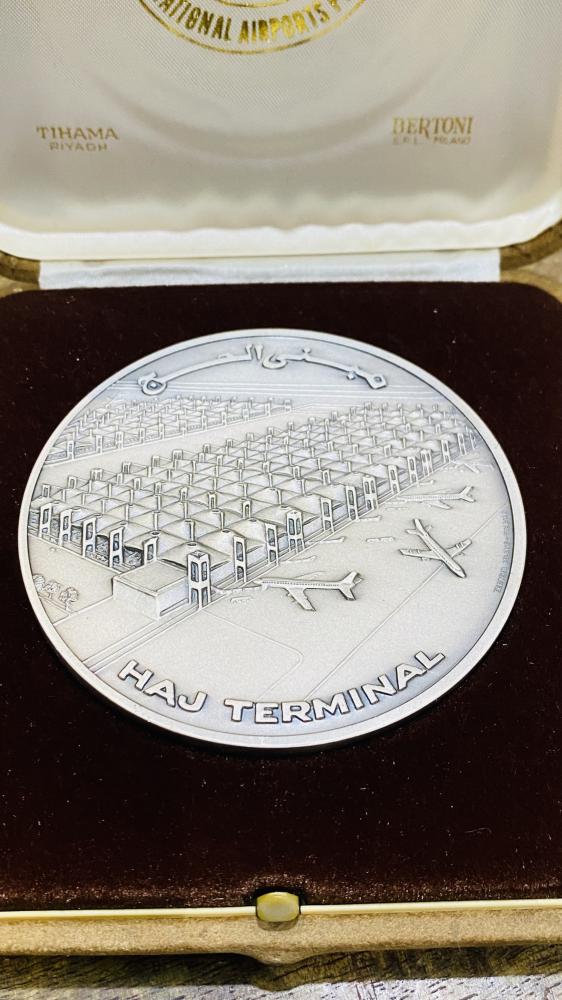 من البنود الشحيحة؛ علبة فاخرة جداً بداخلها ميدالية معدنية ثقيلة الوزن بحجم كبير (واضح حجمها مقارنة بالعملة التي بجانبها فئة الريال) وهي رمزية لمطار الملك عبد العزيز الدولي مؤرخة بعام ١٤٠١هـ - ١٩٨١م تم سكّها في إيطاليا (مقتنى عالي التميز)
