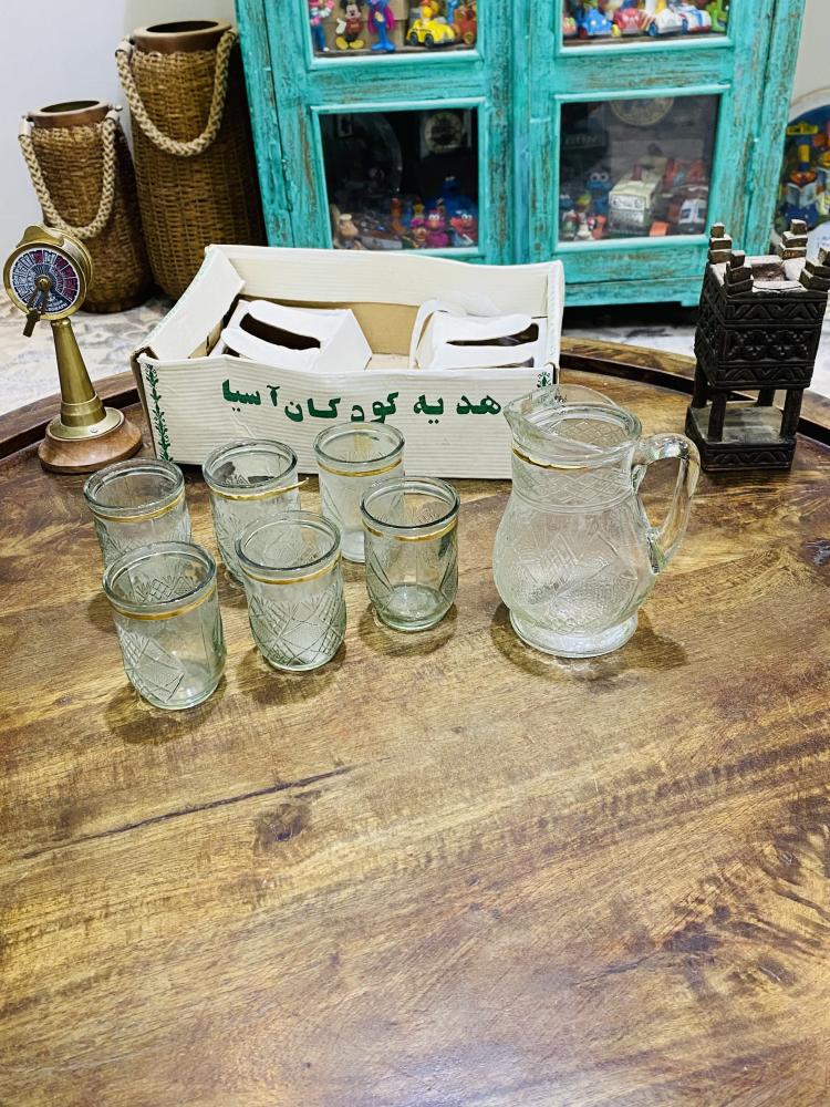 طقم ديكوري من الزجاج المتين جداً بمقاس صغير عبارة عن جيك بإرتفاع ١٥ سم تقريباً وعدد ٦ كاسات بحجم بيالة الشاهي تقريباً؛ قديم ومخزن بالكرتون لم يستخدم