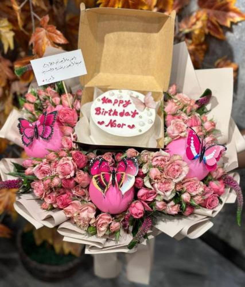 A bouquet of pink roses with a cake stand decorated with accessories
