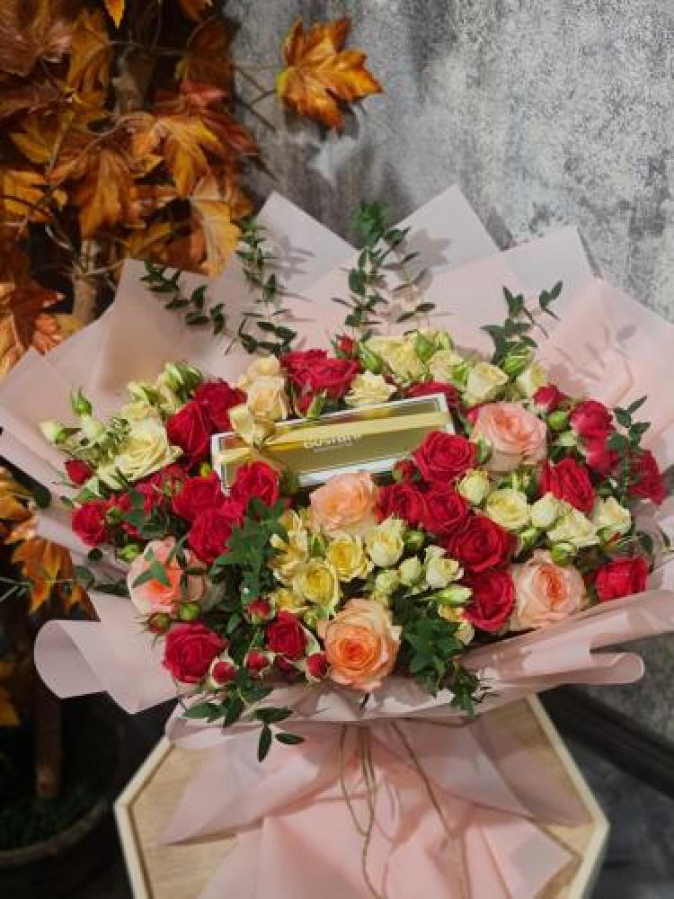 A bouquet of flowers with Bostani chocolates arranged with red and white flowers