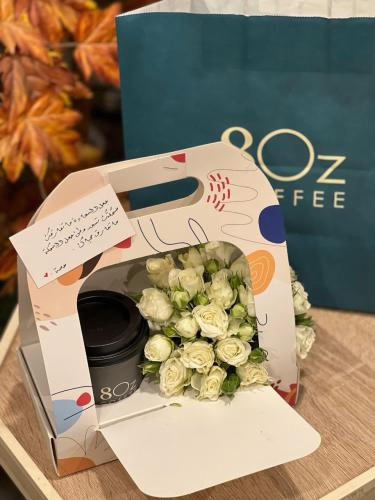 A gift of a white baby pink flower arrangement with a coffee cup