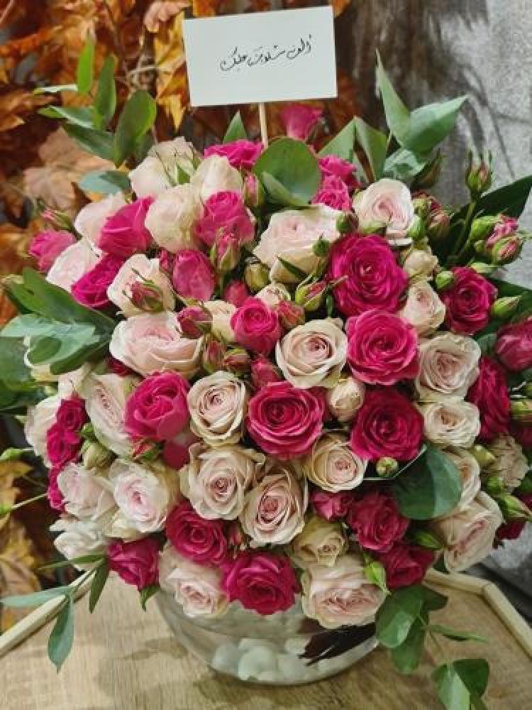 A flower vase with fish arranged with pink roses in shades