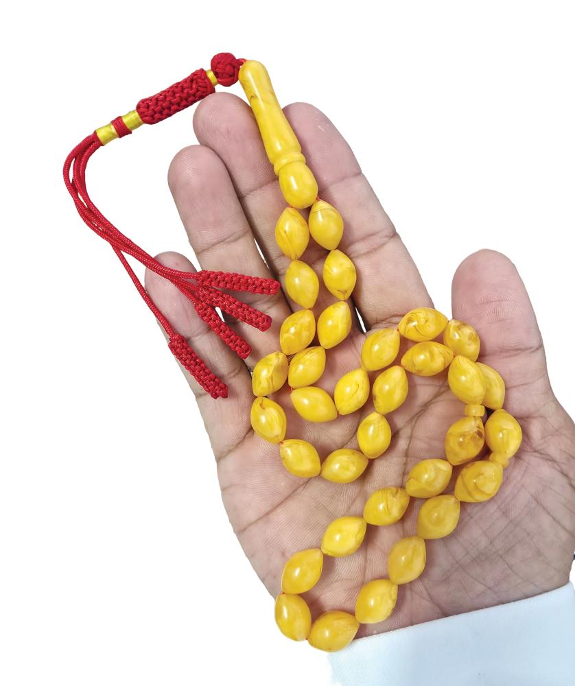 An amber-colored prayer bead, oval-shaped