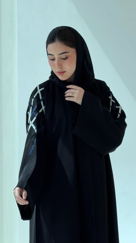 عباية سوداء مطرزة بريش أبيض على الأكتاف