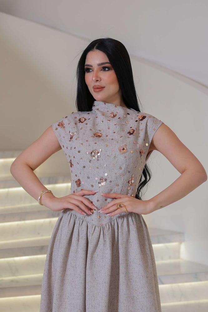 فستان أنيق يجمع بين الرقي الكلاسيكي ولمسة عصرية ناعمة، يتميز بلونه الهادئ ونقوشه اللامعة الرقيقة
