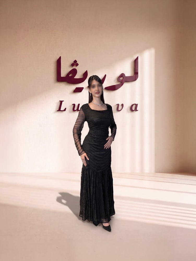فستان أسود فاخر بتطريزات خرز لامعة متدرجة، وأكمام شفافة، مع تنورة دانتيل طويلة وانسيابية