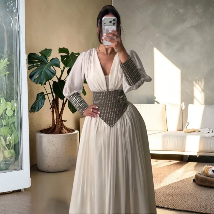 فستان سهرة أبيض بتصميم شيفون منسدل وحزام كريستالي عريض مع أكمام واسعة