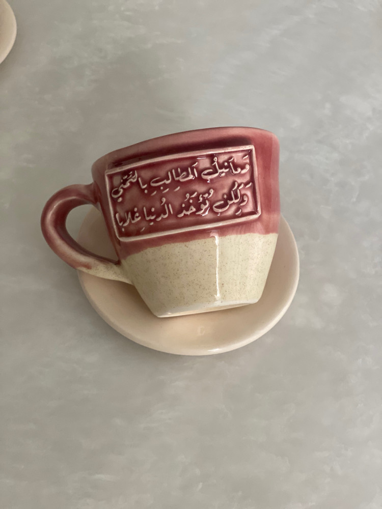 كوب مع طبق بعبارة (وَما نَيلُ المَطالِبِ بِالتَمَنّي ‏وَلَكِن تُؤخَذُ الدُنيا غِلابا)