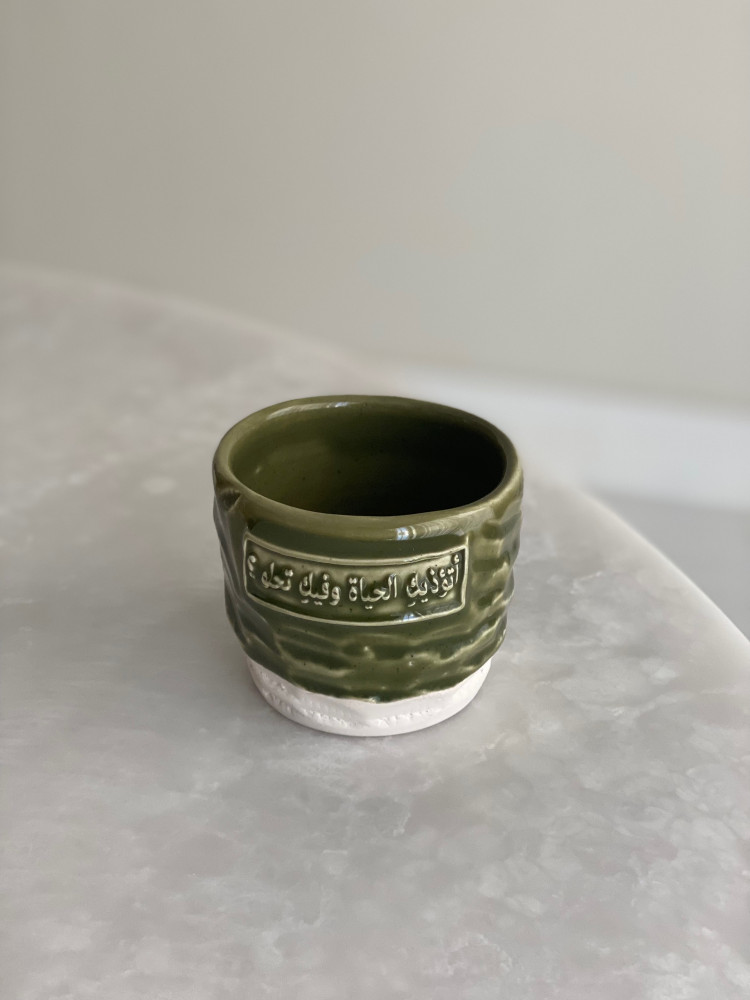 كوب بعبارة ( أتؤذيكِ الحياة وفيكِ تحلو ؟)