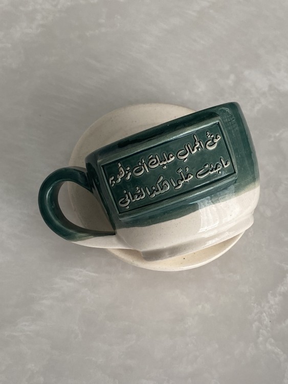 كوب مع طبق بعبارة ( حقُ الجمال عليك أن تزهُو بهِ ‏ ما جئت حُلوًا هكذا لتُعاني)