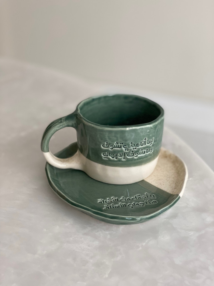 كوب مع طبق بعبارة (ليه أنا عيني تشوف وما تشوف إلا بهاكِ يا أجمل من الأخيله هذا جواب الاسئله)