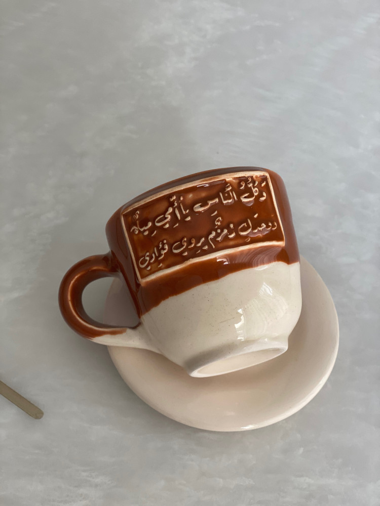 كوب مع طبق بعبارة ( وَكلُّ النَّاسِ يا أُمِّي مِياهٌ ‏وَوحدَكِ زمزمٌ يروِي فؤادِي)