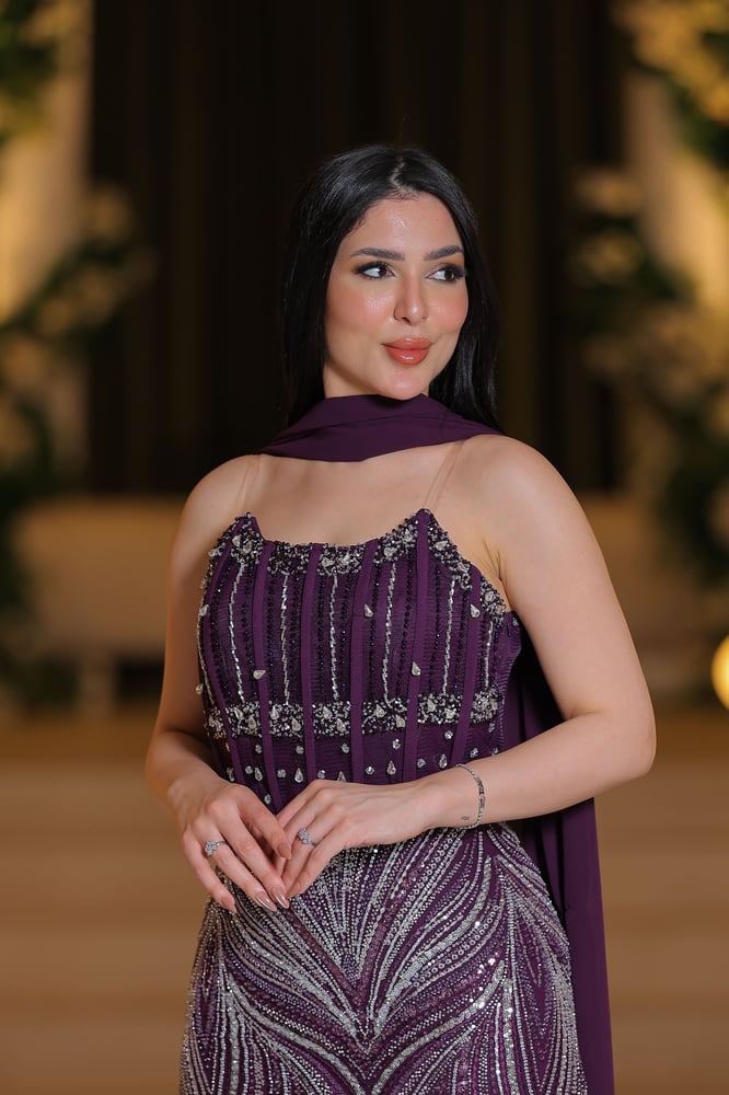 فستان سهرة بنفسجي بتطريز لامع فاخر، مع شال انسيابي يمنح إطلالة أنيقة وجذابة.