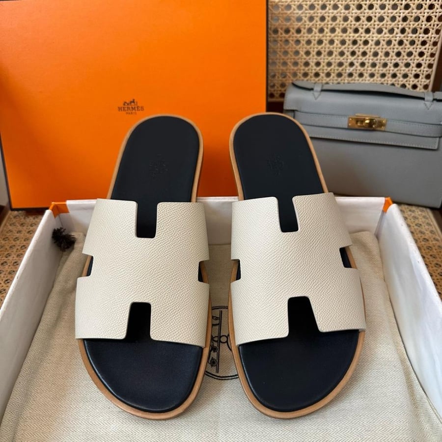 نعال إيزمير (Izmir) الصيفي الفاخر من هرمز (Hermès) من الجلد الطبيعي المحبب باللونين العاجي والأسود.