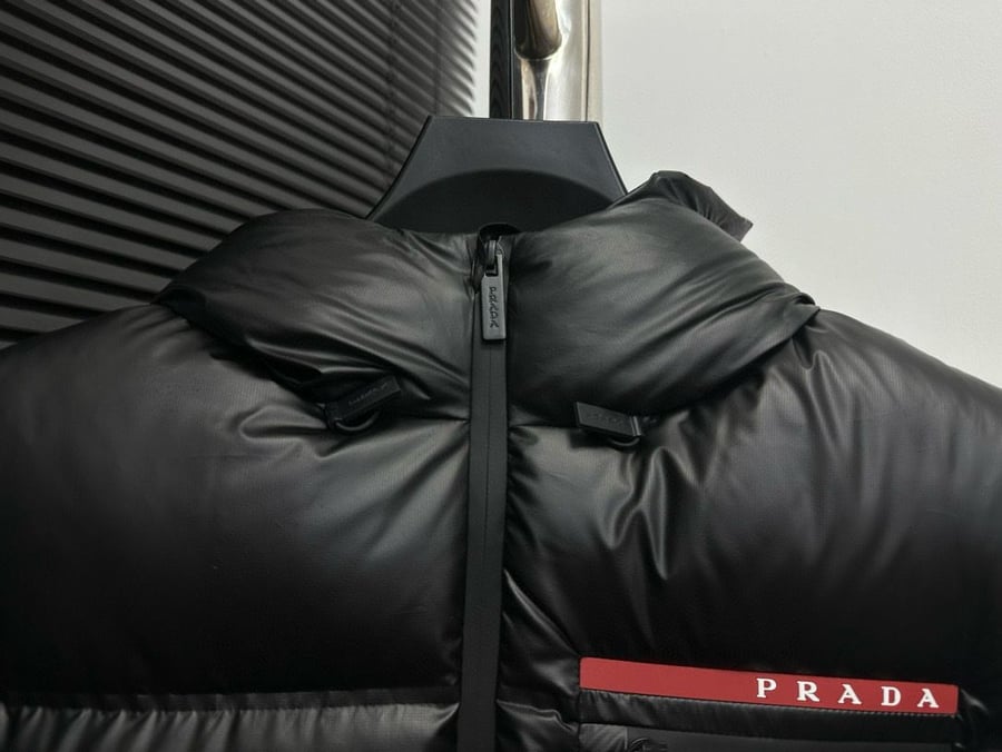 جاكيت / معطف منفوخ رجالي فاخر بقبعة وشعار الدار من "برادا" (Prada) باللون الأسود اللامع