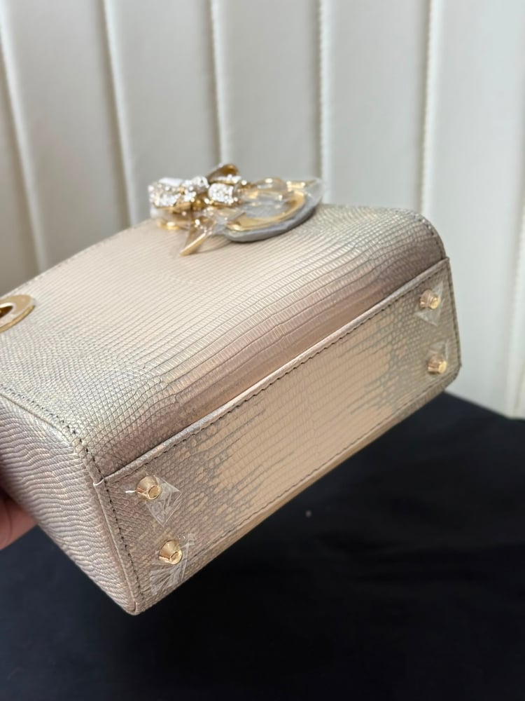 حقيبة ديور (Dior) النسائية الفاخرة بتصميم جلد السحالي مع تعليقة الفيونكة المرصعة