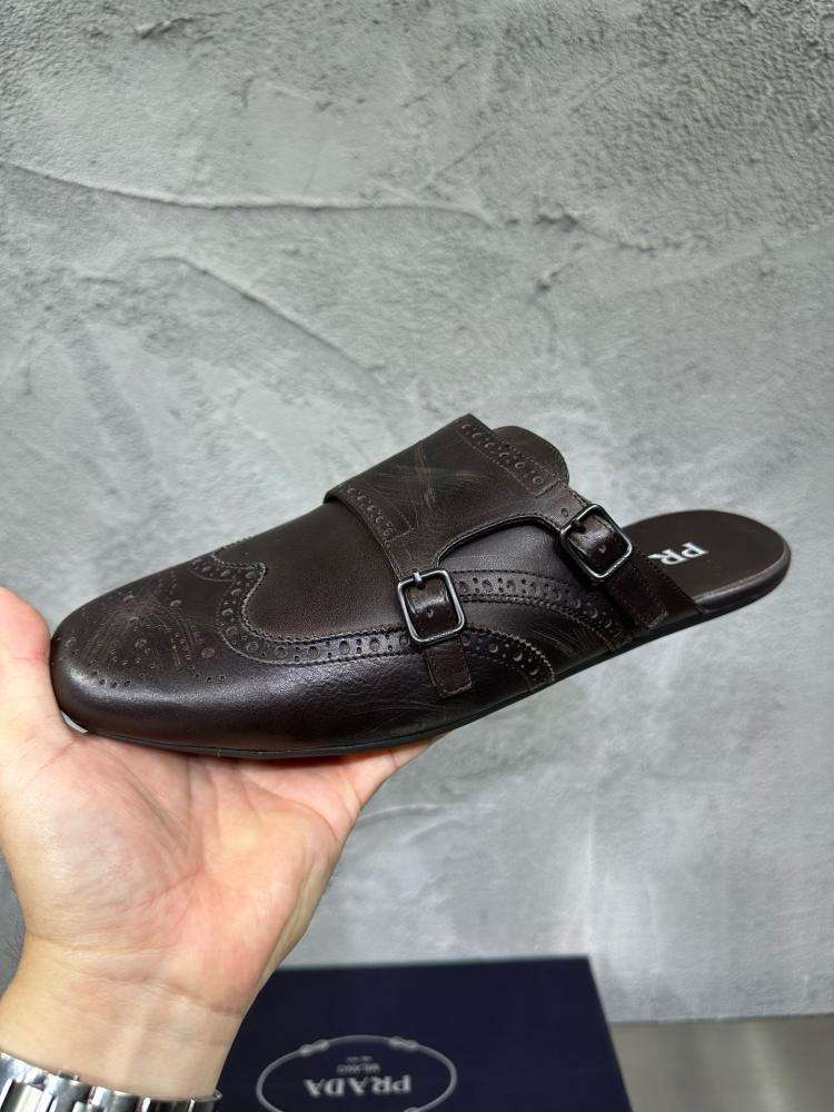 حذاء ميول (Double Monk Strap Mules) كاجوال فاخر بتصميم بروغ من برادا (Prada) من الجلد الطبيعي باللون البني المحروق.