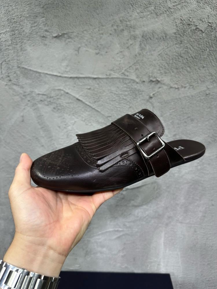 حذاء ميول (Mules) كاجوال فاخر بتصميم بروغ من برادا (Prada) من الجلد الطبيعي باللون البني المحروق.