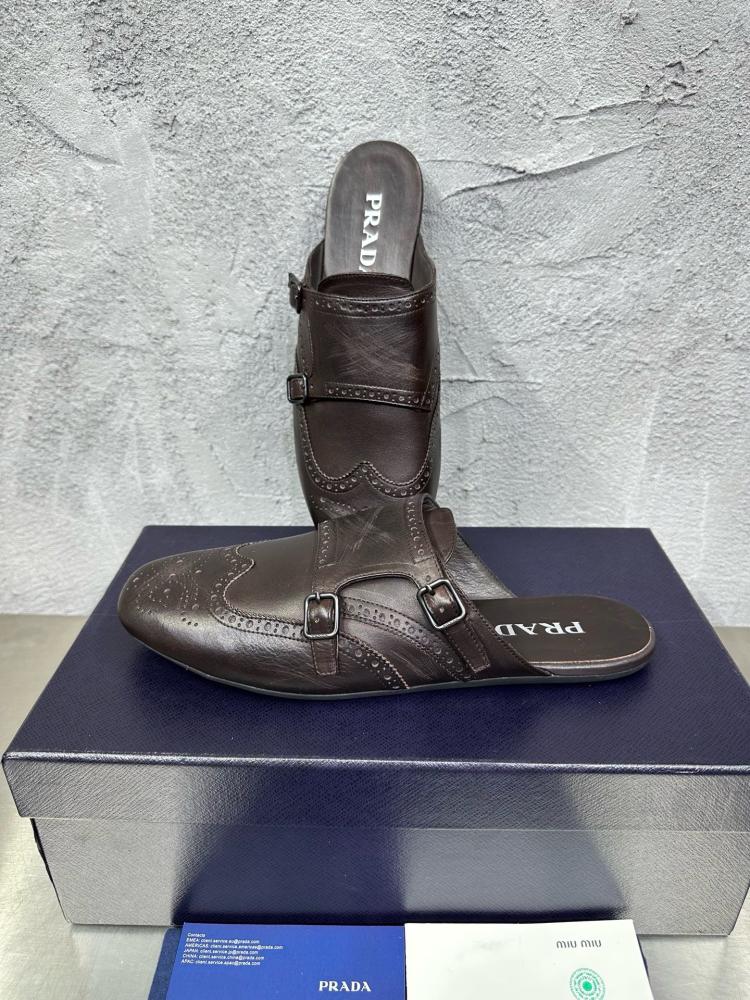 حذاء ميول (Double Monk Strap Mules) كاجوال فاخر بتصميم بروغ من برادا (Prada) من الجلد الطبيعي باللون البني المحروق.