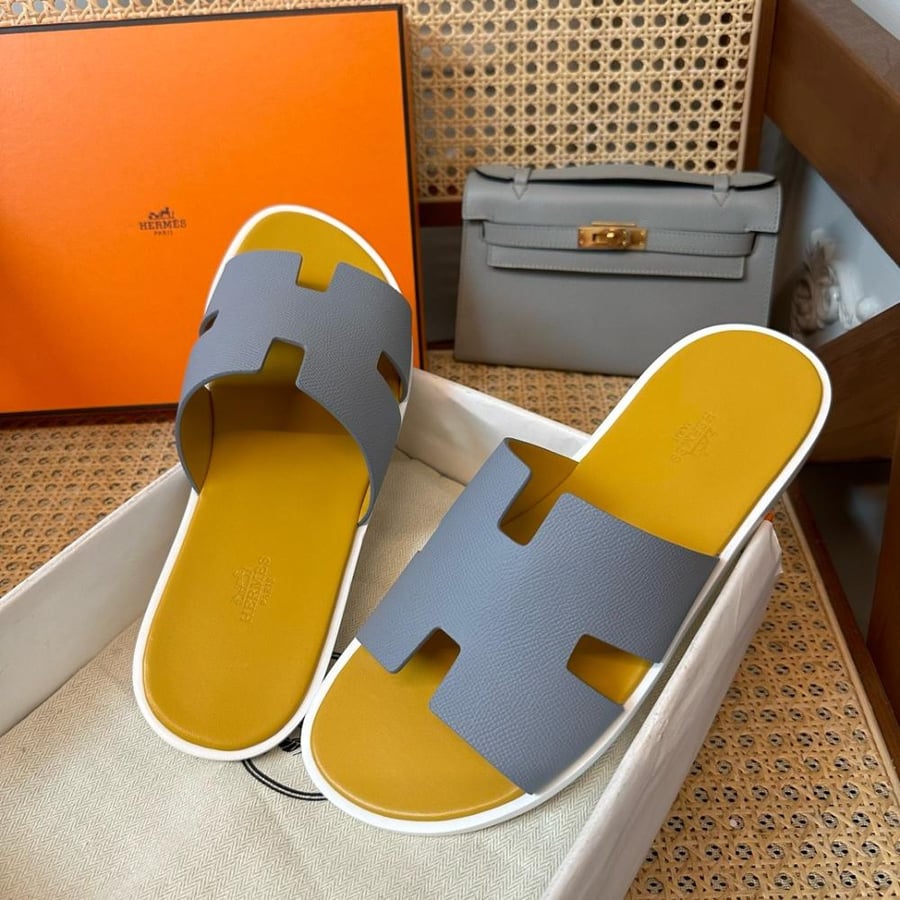 نعال إيزمير (Izmir) الصيفي الفاخر من هرمز (Hermès) من الجلد الطبيعي المحبب باللونين الرمادي الفاتح والأصفر الخردلي.