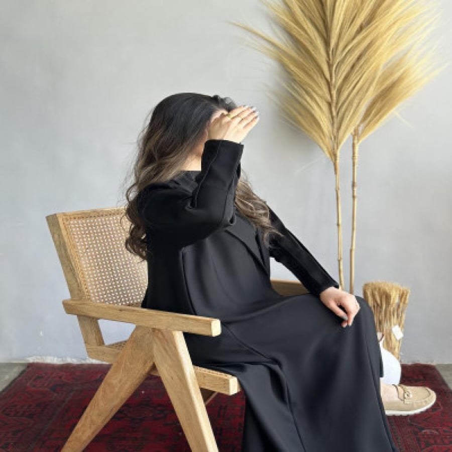 عباية عناقيد سوداء بتصميم أنيق على امرأة جالسة