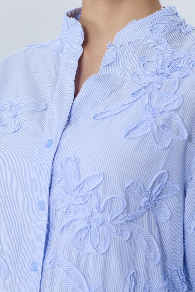 A blouse embroidered with raised flowers in sky blue color