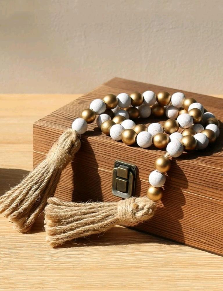 Wooden decor made of beige and gold beads finished with tassels