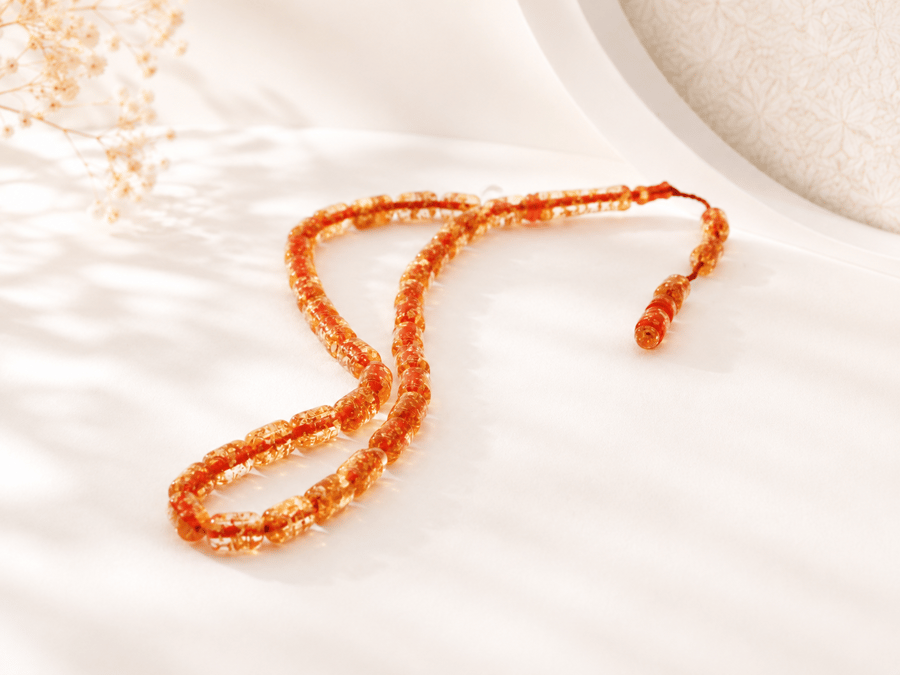 A beaded rosary decorated with gold leaf in shiny orange color
