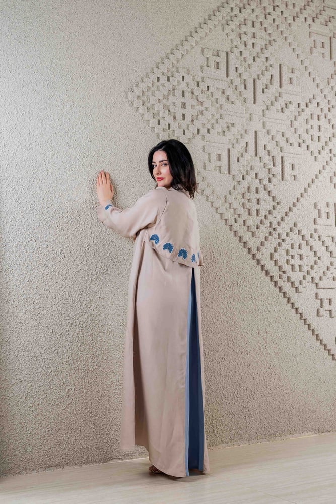 عباية سُلاف بيج بتفاصيل زهور زرقاء وتصميم خلفي مميز