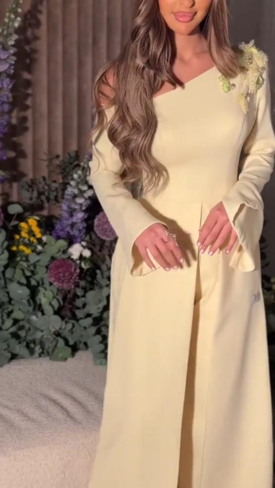 جمبسوت باربي أنيق بلون بيج (أوف وايت) بتصميم كتف واحد ومزين بتطريز يدوي على الكتف مع أكمام واسعة وثنيات عند الخصر
