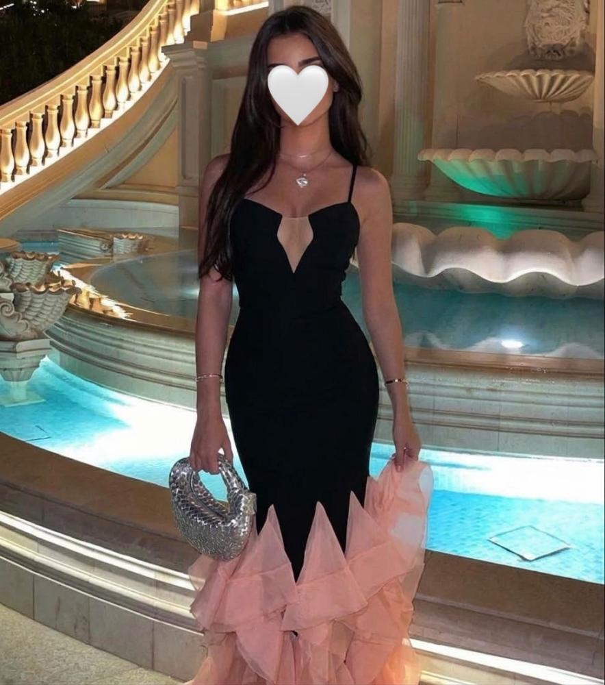 فستان سهرة أسود أنيق بقصة الحورية (الميرميد) وفتحة صدر V جذابة، يكتمل بذيل فاخر من طبقات الشيفون المتموجة باللون الوردي المشمشي.