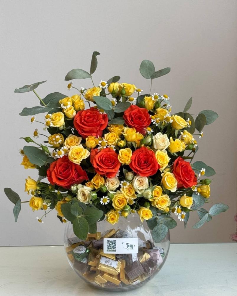 A kilogram of chocolate rolls with a vase of roses