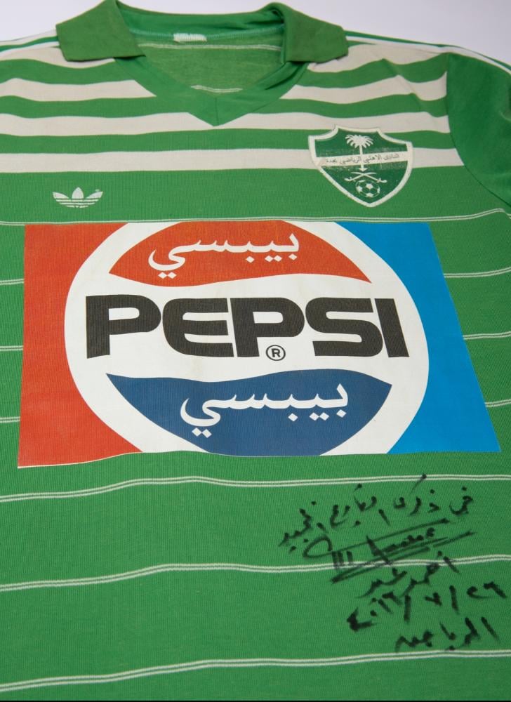 قميص للاعب نادي الاهلي السعودي أحمد الصغير "رحمه الله" يعود لعام ١٩٨٧م يحمل توقيع الكابتن أحمد عيد.  هذا العام تحديداً شهد احتفال النادي الأهلي بمرور ٥٠ عاماً على تأسيسه (اليوبيل الذهبي) وهو ذات الطقم الشهير الذي ارتداه الأسطورة الأرجنتينية دييغو مارادونا