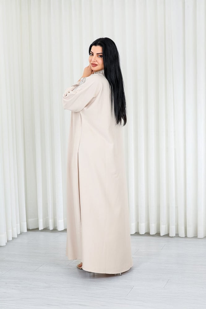 A long, ankle-length fabric jalabiya decorated with vertical embroidery on the chest.