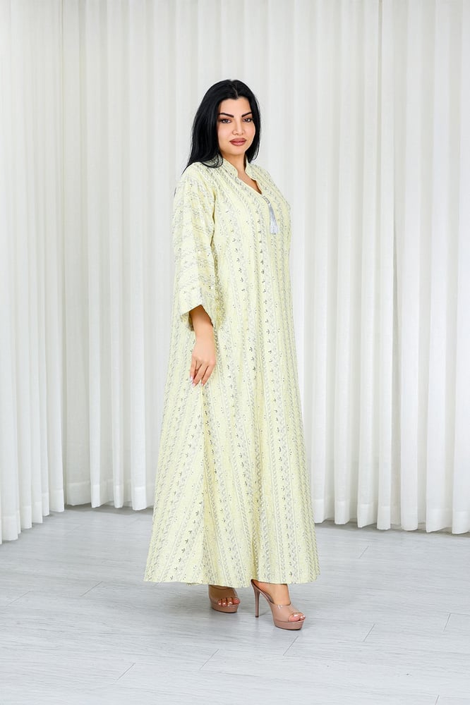 A long, ankle-length fabric jalabiya with wide sleeves and a small open neckline, adorned with small geometric embroidery across the entire fabric.
