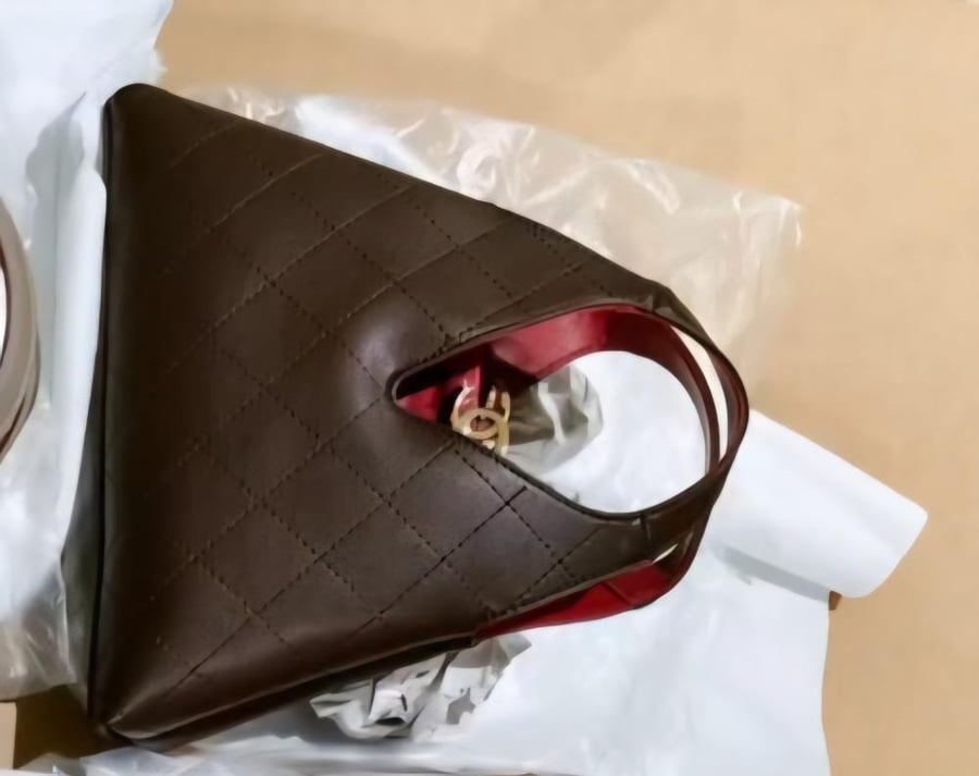حقيبة يد سوداء مبطنة من شانيل (Chanel Chic Lady) تتميز بتصميم هندسي هندسي فريد وبطانة داخلية حمراء زاهية مع قفل شعار CC الذهبي.