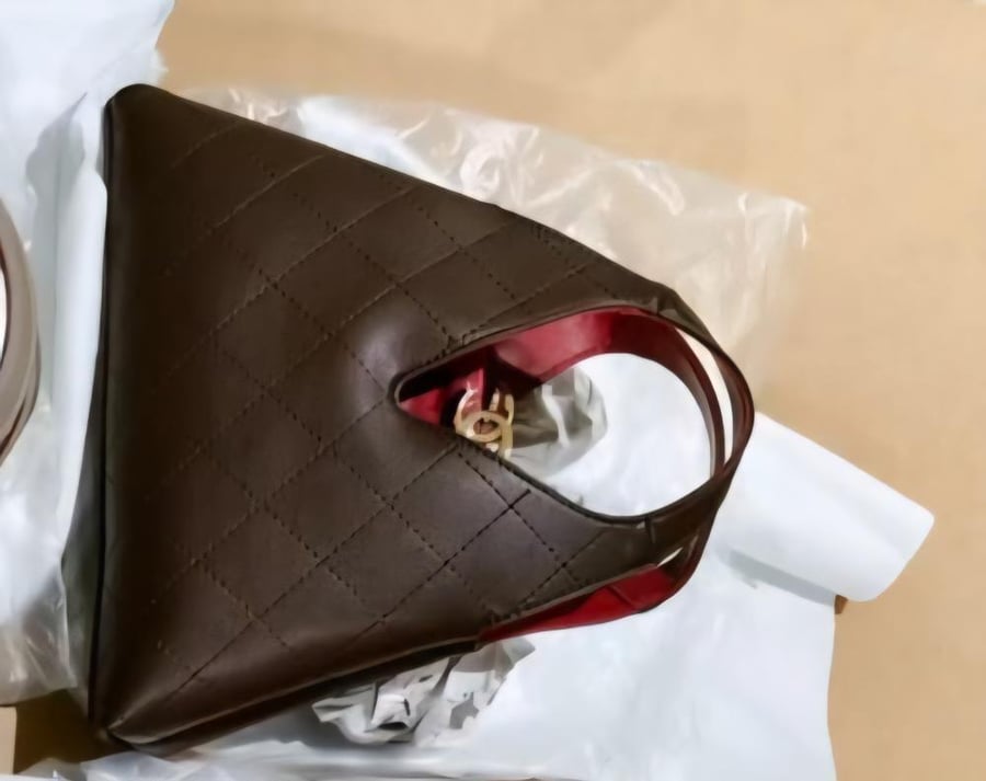 حقيبة يد سوداء مبطنة من شانيل (Chanel Chic Lady) تتميز بتصميم هندسي هندسي فريد وبطانة داخلية حمراء زاهية مع قفل شعار CC الذهبي.