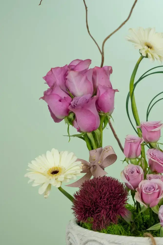 تنسيق زهور وردية متنوعة في أصيص أبيض مزخرف