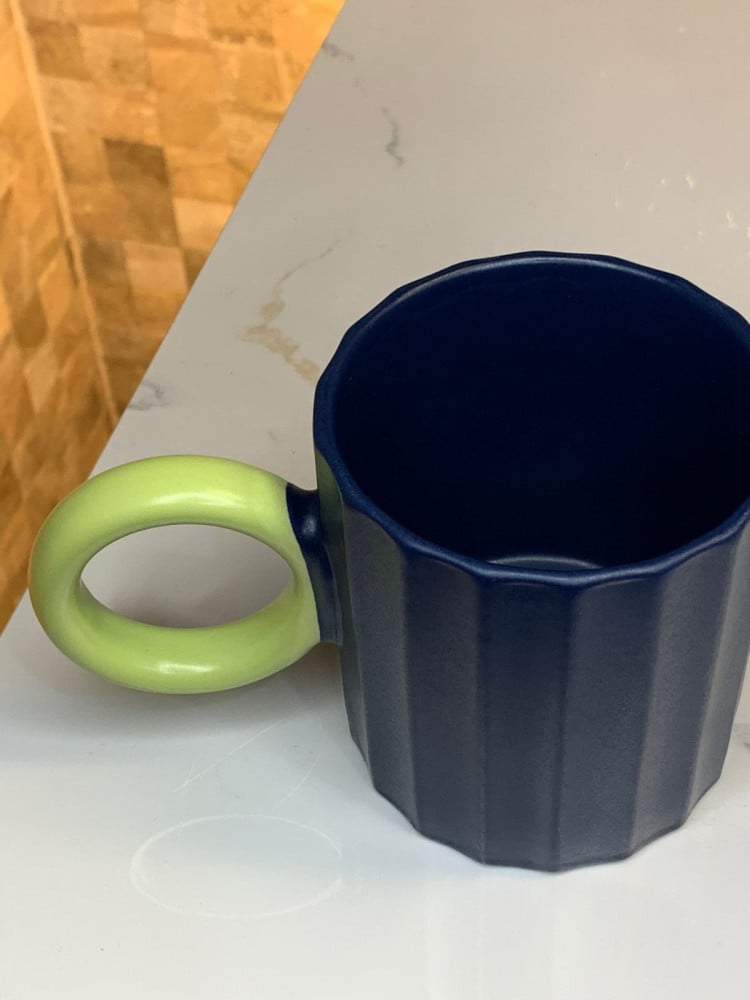 Ceramic cup with a blue and green handle