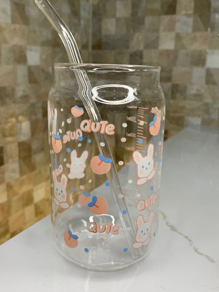 Glass cup with a rabbit illustration and a straw