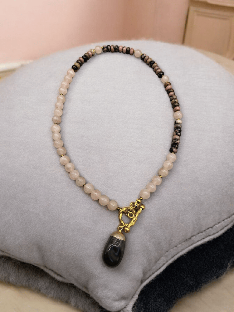 A necklace of femininity stone rose quartz with a stone of rhodonite and decorated with a piece of black onyx stone.