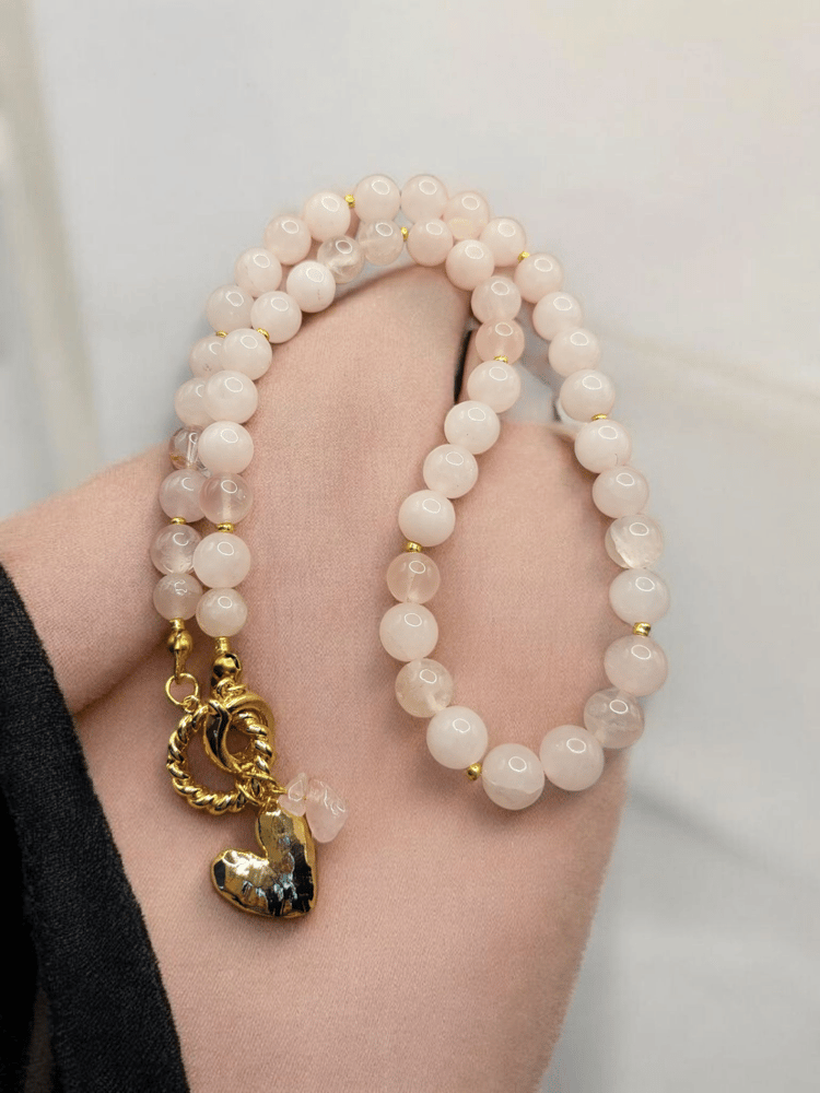A necklace of rose quartz stone enhanced for femininity with a gold-plated charm