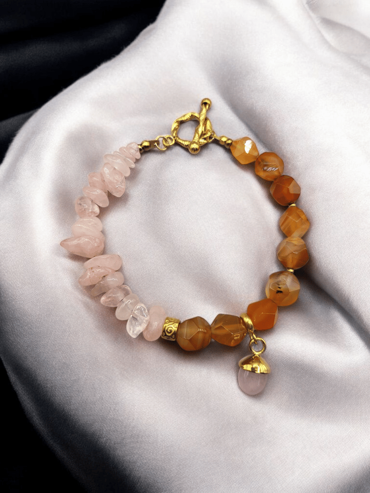 An elegant and distinctive bracelet made of carnelian agate with broken rose quartz stone and decorated with gold-plated charms, for daily wear.