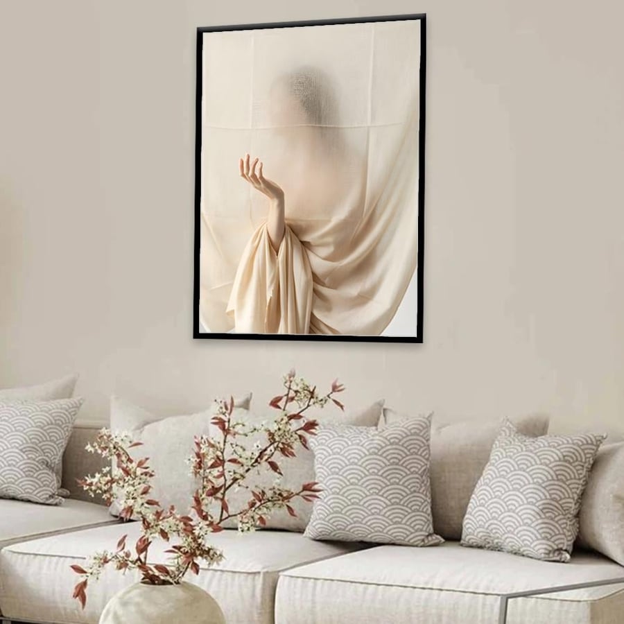 لوحة ملامح إنسانية خلف قماش شفاف كريمي فوق كنبة بيضاء وأغصان قطن