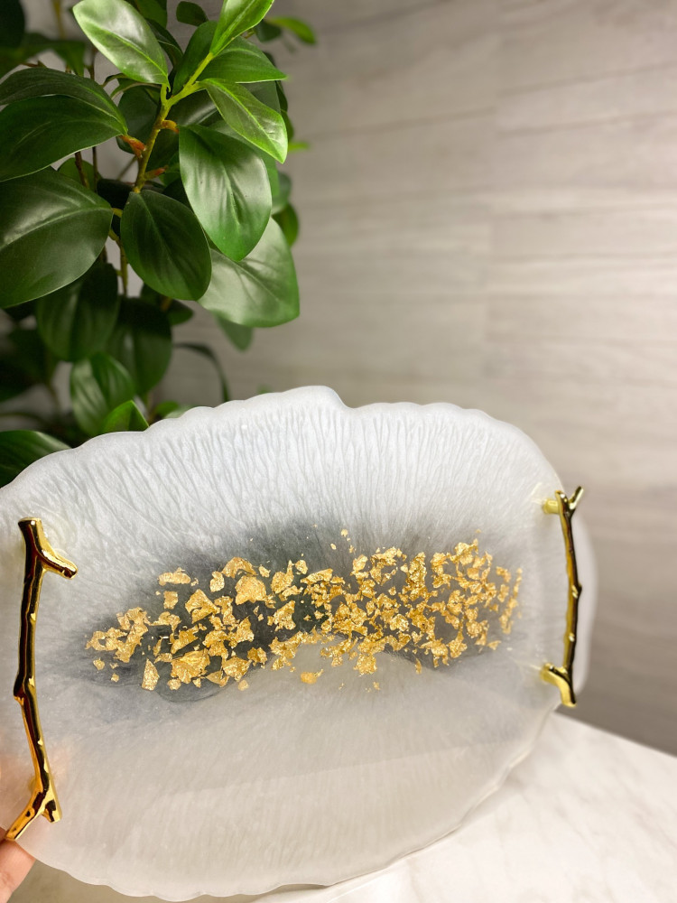 A tray in pearl color with golden branch handles