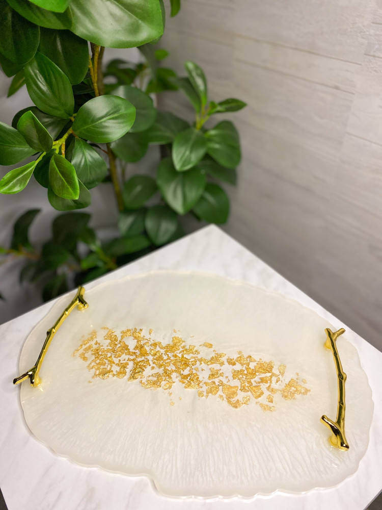 A tray in pearl color with golden branch handles